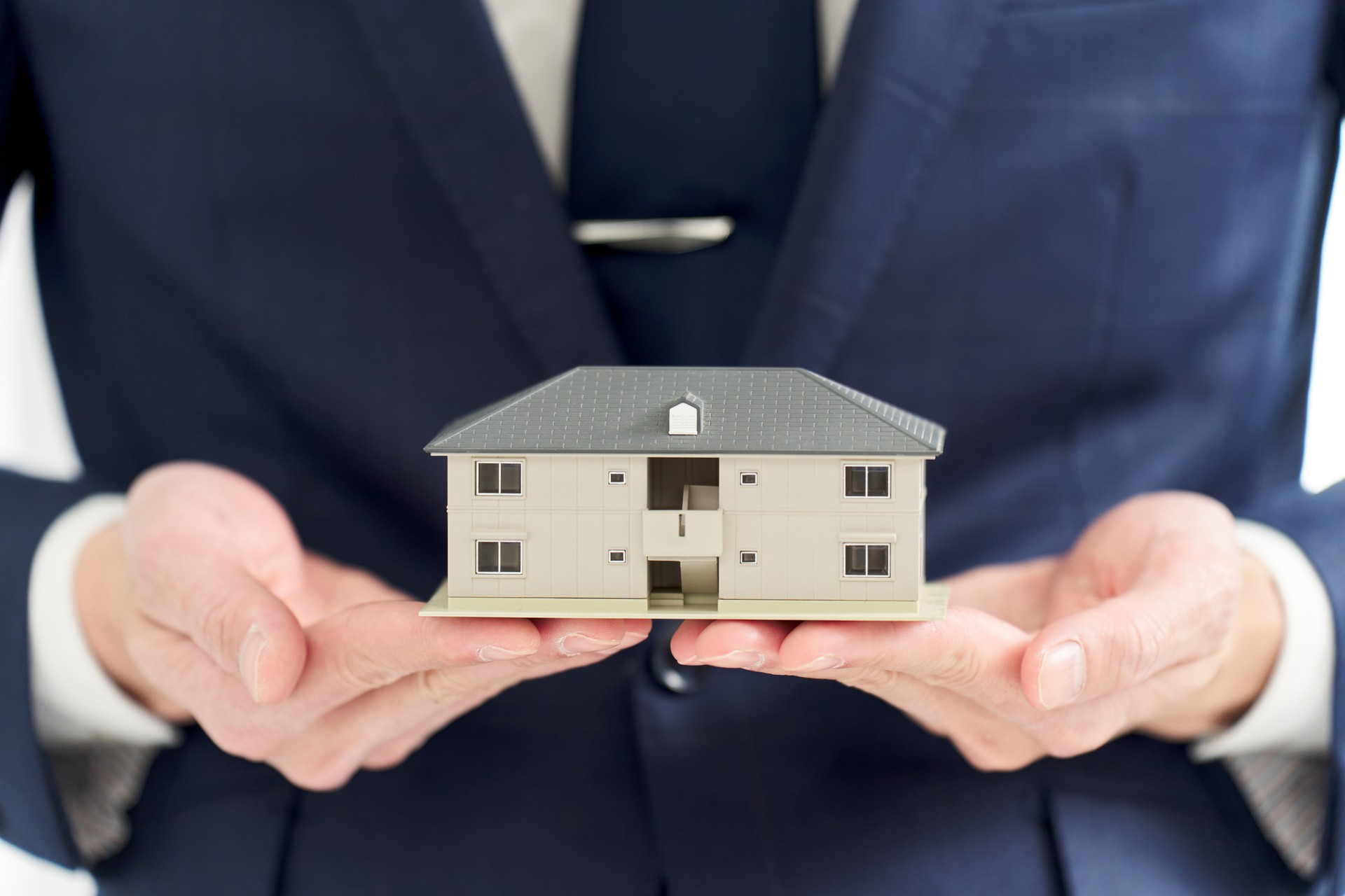 Businessman's hand holding a model of an apartment